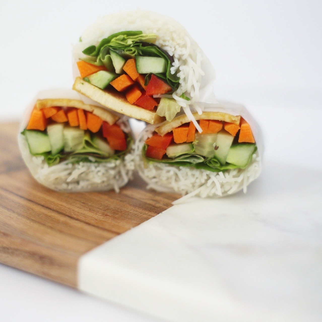 Tofu salad rolls on marble and wood serving board